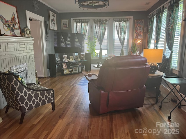 130 Arlington St, Forest City, NC 28043 - living area featuring plenty of natural light, a brick fireplace, wood finished floors, and crown molding