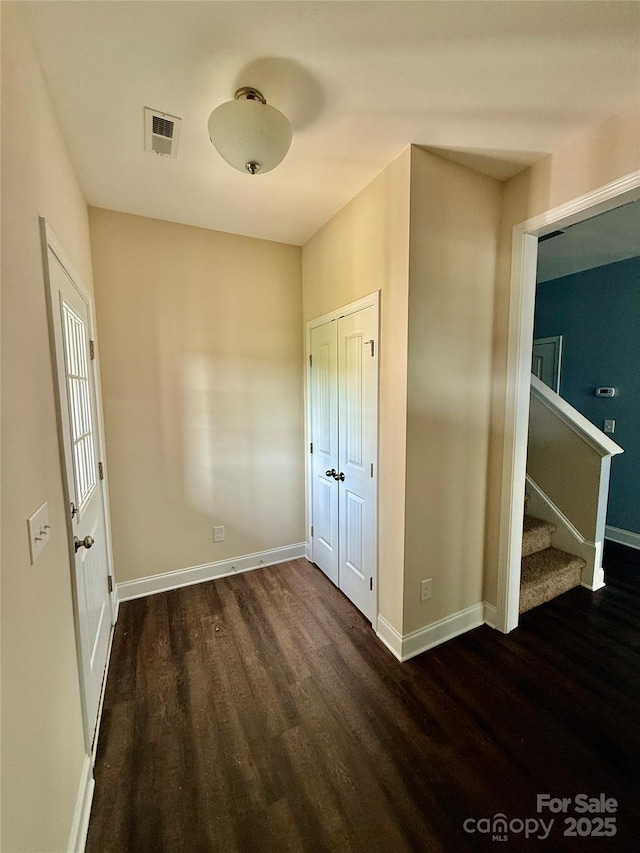 foyer with baseboards, stairs, wood finished floors, and visible vents
