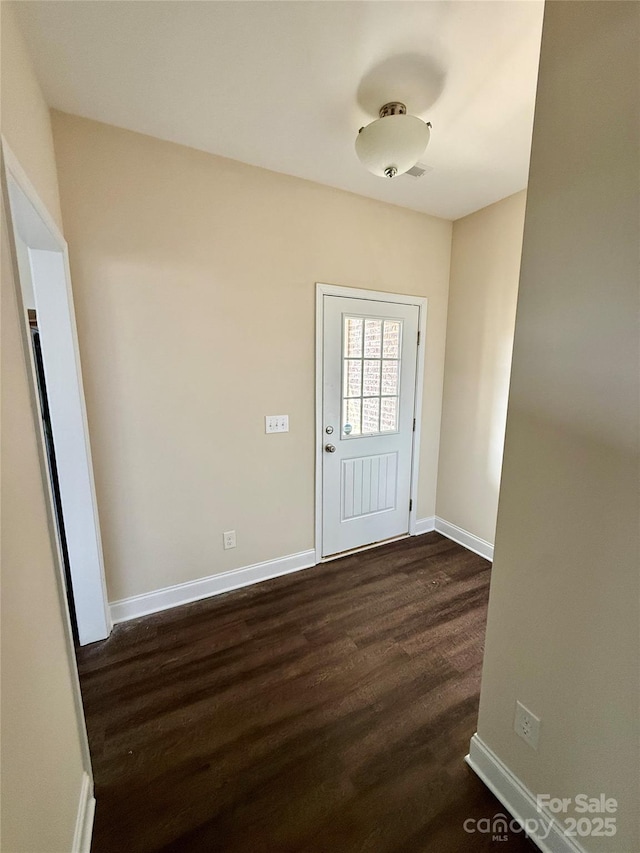doorway to outside featuring baseboards and dark wood-type flooring