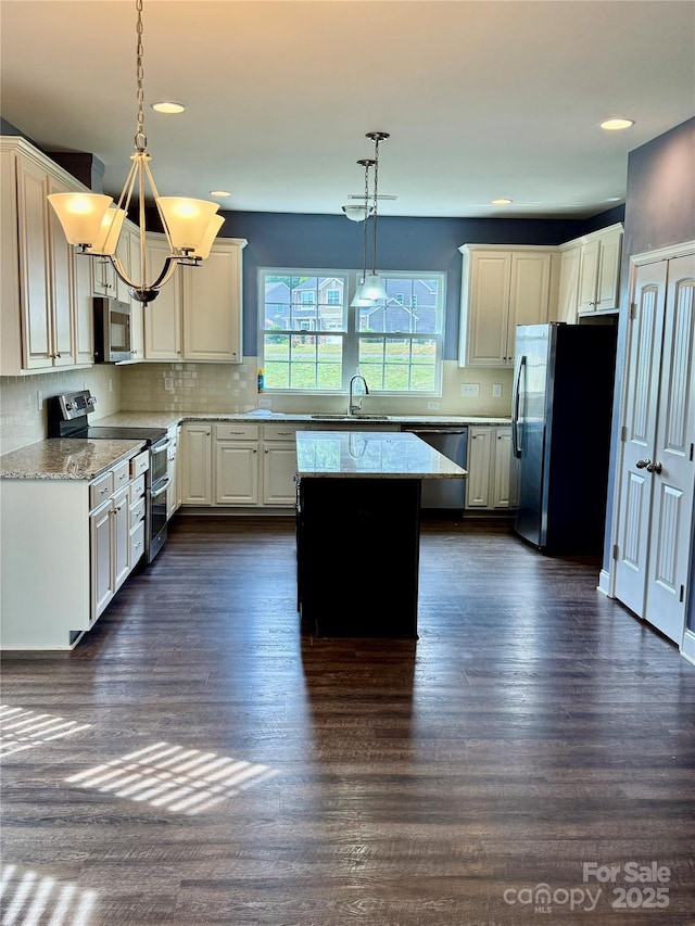 kitchen featuring appliances with stainless steel finishes, tasteful backsplash, a sink, and a center island