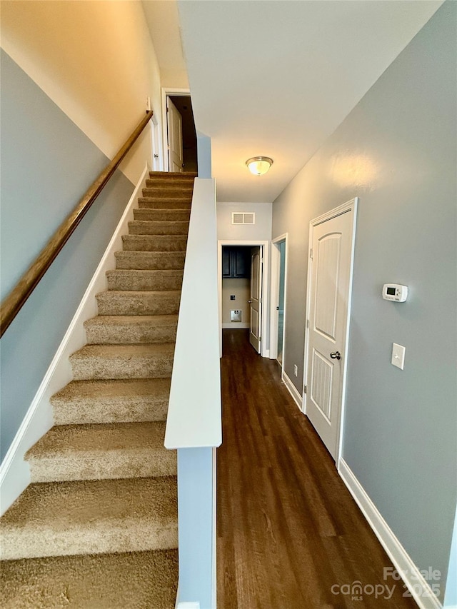 stairway with baseboards, visible vents, and wood finished floors