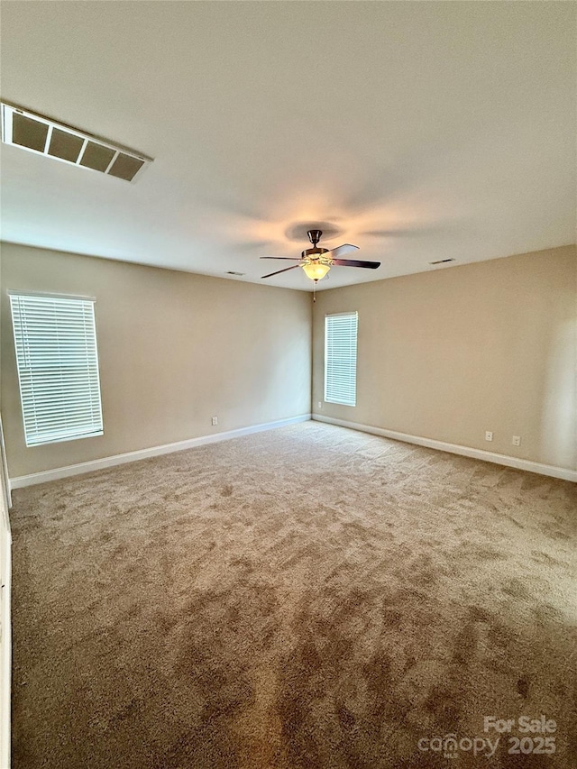 carpeted empty room with baseboards, ceiling fan, and visible vents