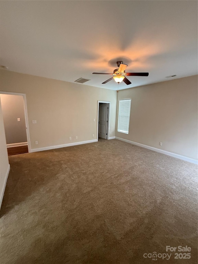 carpeted spare room with ceiling fan, visible vents, and baseboards