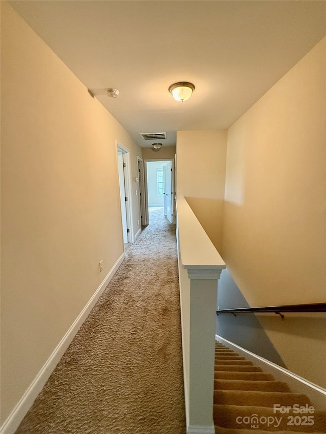 hallway featuring baseboards, carpet flooring, and visible vents