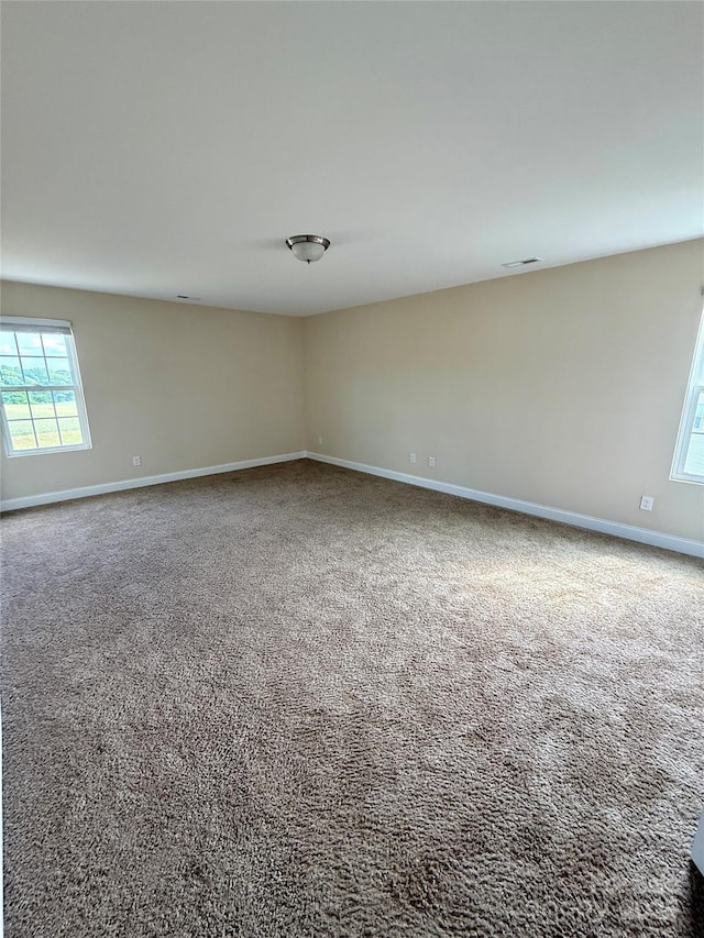 unfurnished room with carpet floors, baseboards, and visible vents