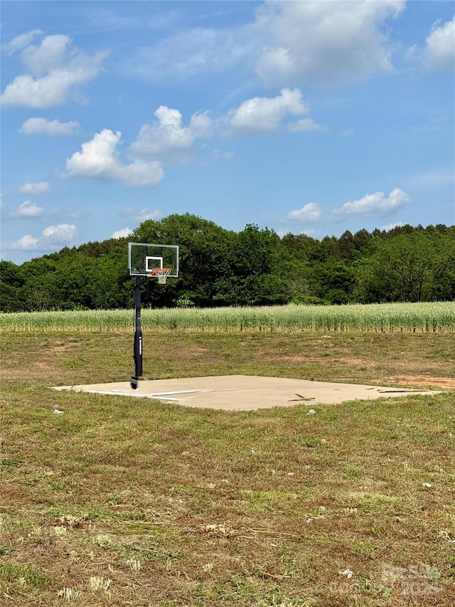 view of sport court featuring a yard and a wooded view