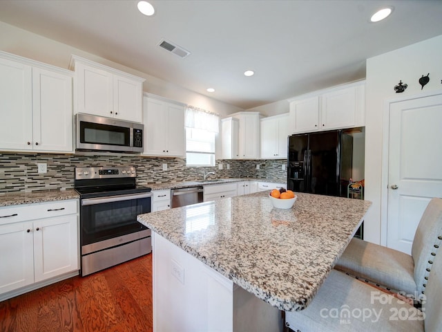 6266 Swanport Rd, Lancaster, SC 29720 - kitchen with appliances with stainless steel finishes, a breakfast bar, dark wood-style floors, white cabinets, and decorative backsplash