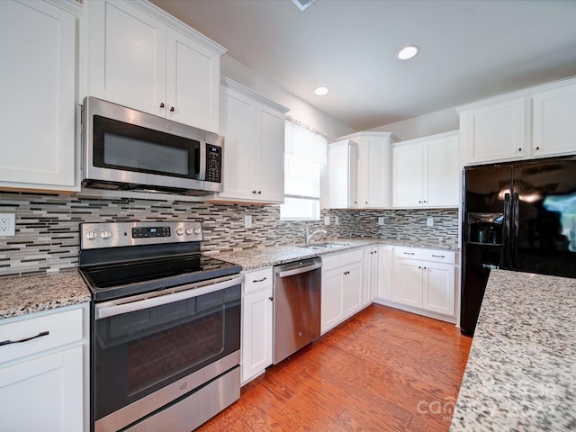 6266 Swanport Rd, Lancaster, SC 29720 - kitchen with stainless steel appliances, a sink, white cabinetry, light wood-style floors, and tasteful backsplash