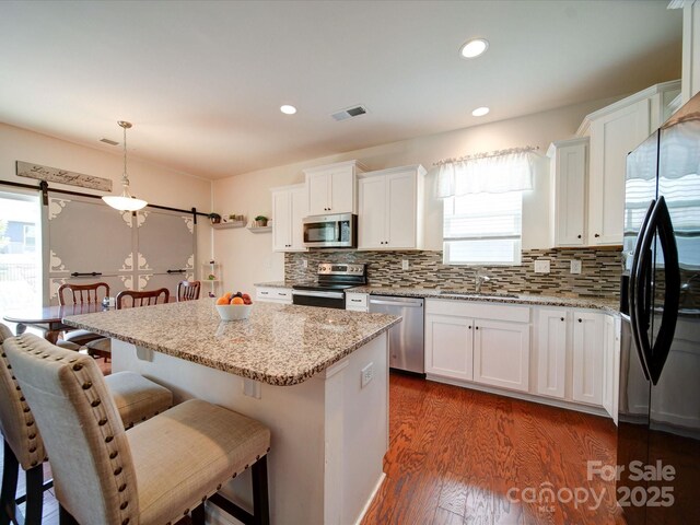6266 Swanport Rd, Lancaster, SC 29720 - kitchen with appliances with stainless steel finishes, dark wood-style floors, backsplash, a breakfast bar area, and white cabinets
