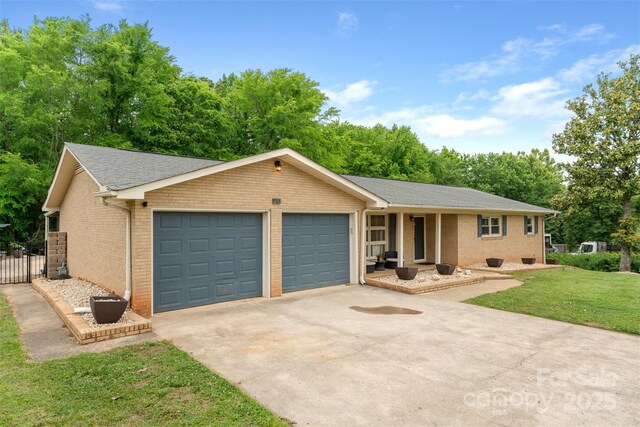 213 Lakeview Dr, Harrisburg, NC 28075 - ranch-style house with an attached garage, driveway, brick siding, a shingled roof, and view of wooded area