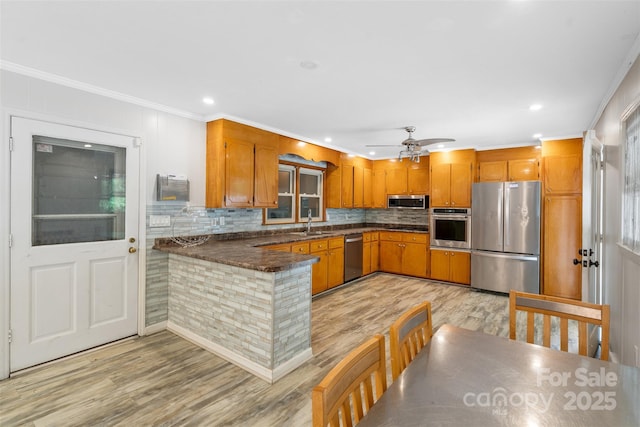 213 Lakeview Dr, Harrisburg, NC 28075 - kitchen featuring appliances with stainless steel finishes, a peninsula, light wood-style floors, ornamental molding, and a ceiling fan