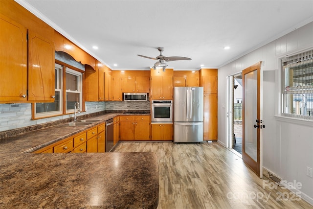 213 Lakeview Dr, Harrisburg, NC 28075 - kitchen featuring appliances with stainless steel finishes, a sink, brown cabinetry, light wood finished floors, and dark countertops