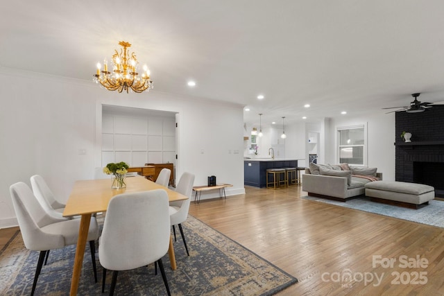 dining room featuring wood finished floors, ceiling fan, a chandelier, recessed lighting, and a fireplace