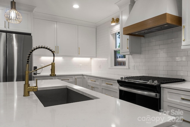 kitchen with premium range hood, freestanding refrigerator, range with gas stovetop, a sink, and tasteful backsplash