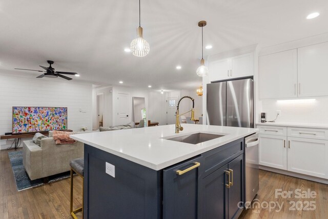 kitchen with a sink, open floor plan, stainless steel appliances, white cabinets, and dark wood finished floors