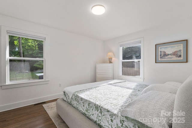 bedroom with multiple windows, dark wood-style floors, and baseboards