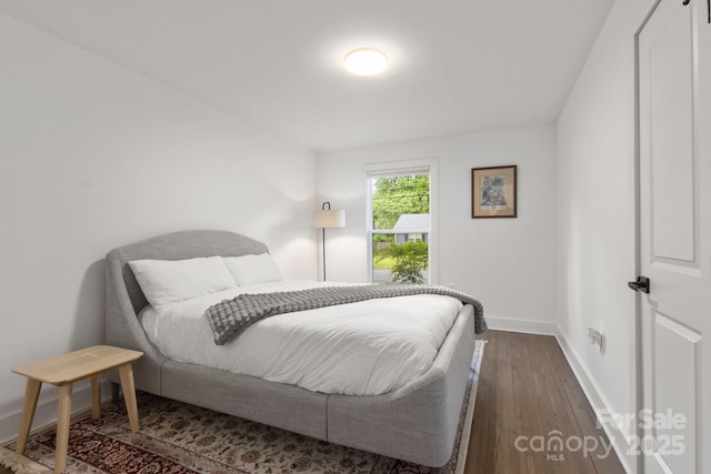 bedroom with baseboards and dark wood finished floors