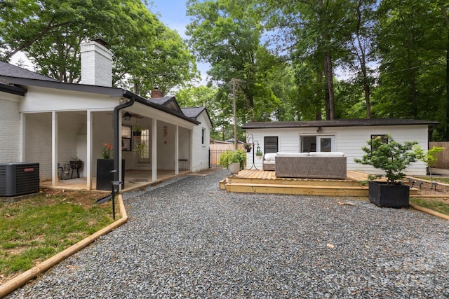rear view of property with a chimney, a deck, central air condition unit, a patio, and fence
