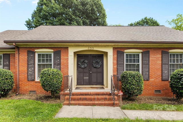doorway to property with crawl space, brick siding, and a shingled roof