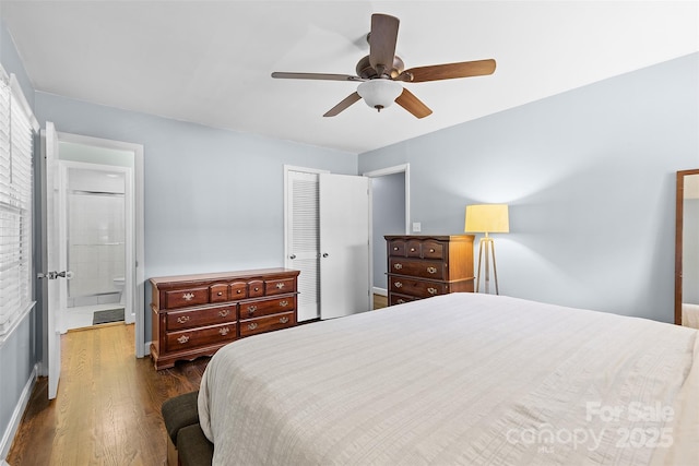 bedroom with a closet, dark wood-style flooring, ceiling fan, baseboards, and connected bathroom