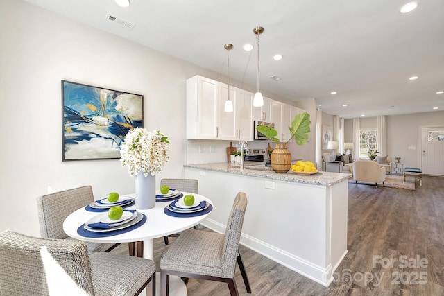 514 Rich St, Rock Hill, SC 29730 - kitchen with visible vents, wood finished floors, light stone countertops, white cabinetry, and stainless steel microwave