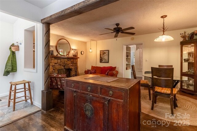 kitchen featuring a stone fireplace, dark wood-type flooring, a ceiling fan, wood counters, and decorative light fixtures