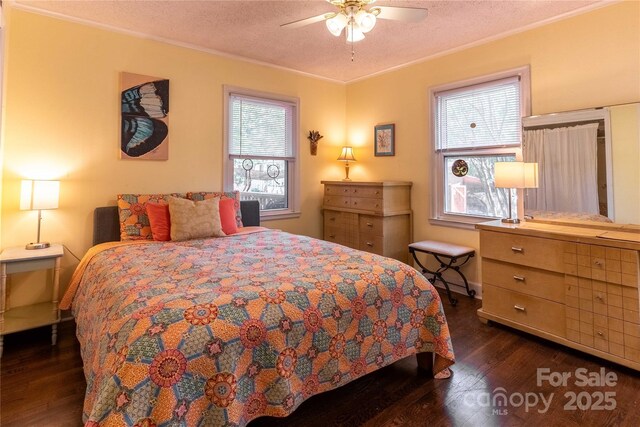 bedroom featuring a textured ceiling, dark wood finished floors, ornamental molding, and ceiling fan