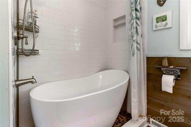 bathroom with tile walls and a soaking tub