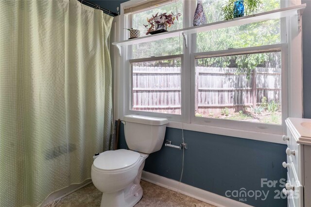 bathroom featuring toilet, baseboards, plenty of natural light, and vanity