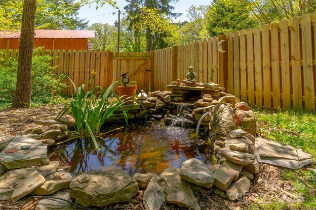 exterior space with a fenced backyard and a garden pond