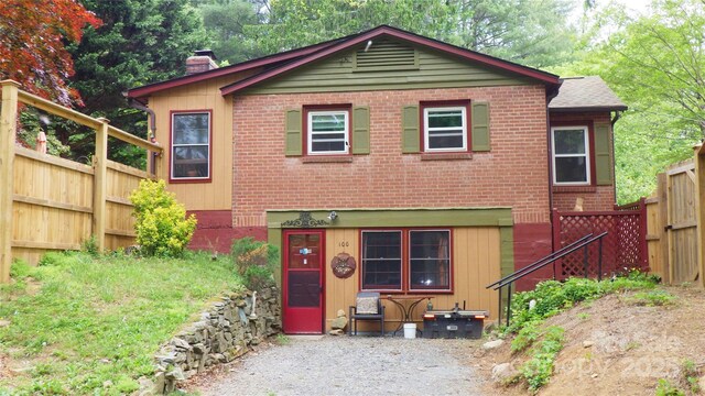 view of front of house featuring brick siding, fence, and a chimney
