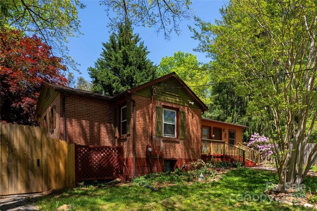 rear view of property with a lawn, brick siding, and fence