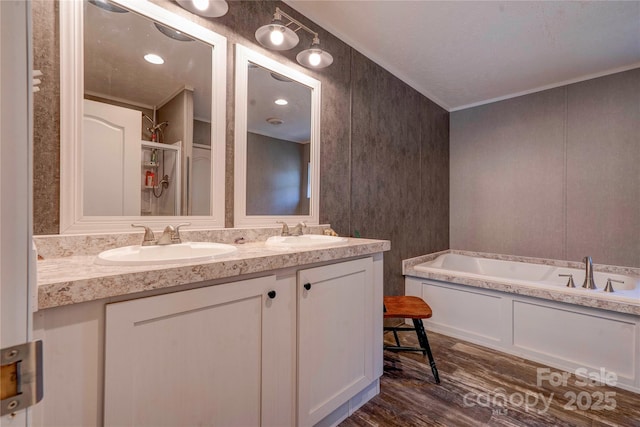 bathroom with a garden tub, a sink, wood finished floors, and double vanity
