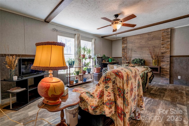 living room with a textured ceiling, ceiling fan, and wood finished floors