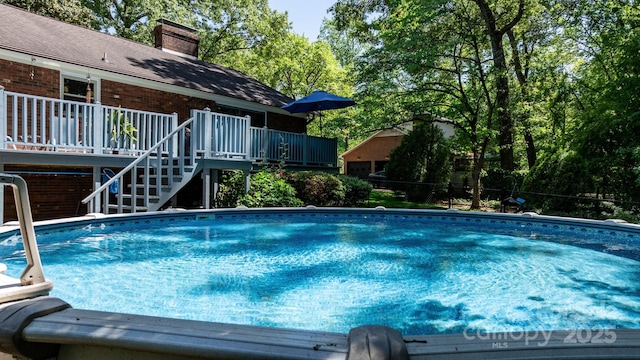 outdoor pool featuring stairs and a deck