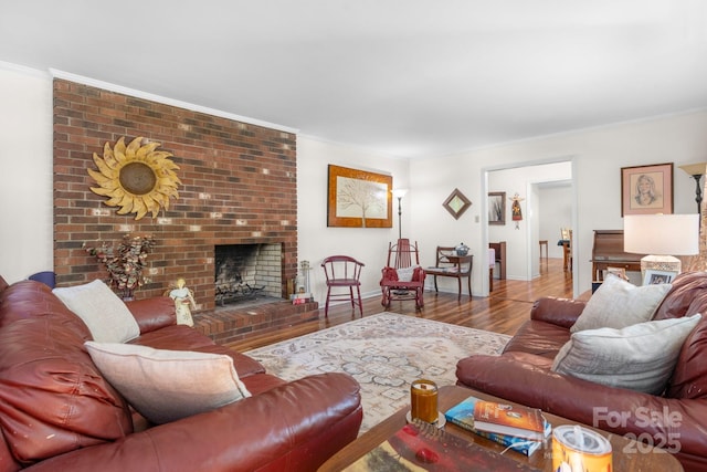 living room with crown molding, baseboards, a brick fireplace, and wood finished floors
