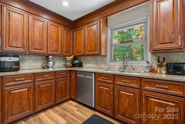 kitchen with stainless steel dishwasher, light wood-type flooring, tasteful backsplash, light stone counters, and a sink