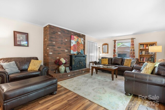 living area featuring a brick fireplace, crown molding, and wood finished floors