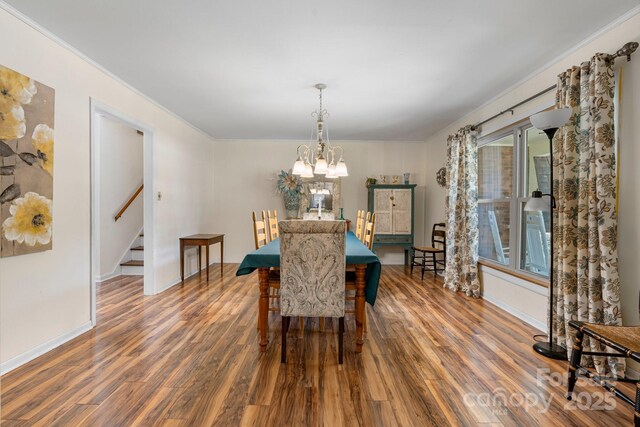 dining room with stairs, a chandelier, ornamental molding, and wood finished floors
