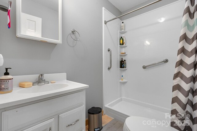 bathroom featuring wood finished floors, toilet, curtained shower, and vanity