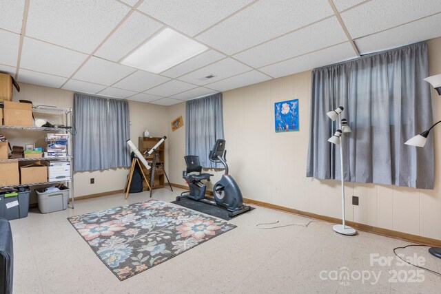 exercise area featuring baseboards, tile patterned floors, and a paneled ceiling