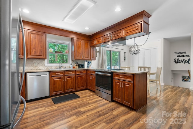 701 5th Ave NE, Conover, NC 28613 - kitchen featuring appliances with stainless steel finishes, a peninsula, light wood-style floors, under cabinet range hood, and healthy amount of natural light