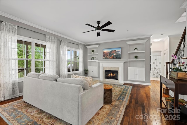 422 Deer Brush Ln, Waxhaw, NC 28173 - living room featuring dark wood finished floors, ceiling fan, a fireplace, crown molding, and built in features