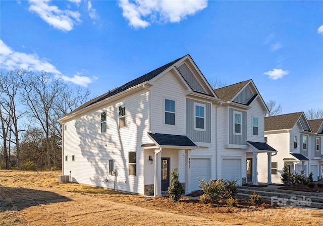 view of front of home with dirt driveway, board and batten siding, an attached garage, and cooling unit