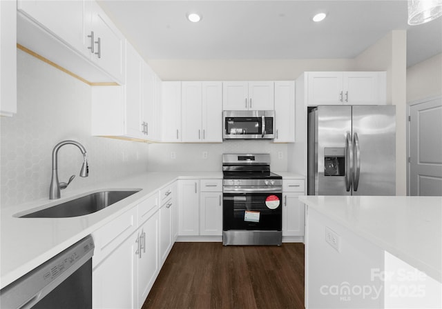 kitchen with dark wood-type flooring, light countertops, white cabinetry, a sink, and stainless steel appliances