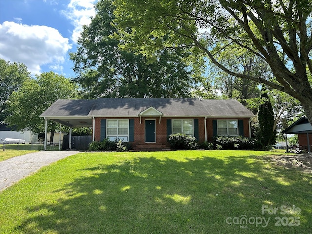 ranch-style home featuring a front lawn, fence, an attached carport, brick siding, and driveway