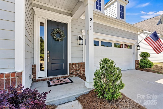 entrance to property with brick siding, driveway, and a garage
