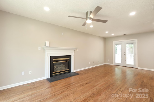 2011 Redwood Dr, Indian Trail, NC 28079 - unfurnished living room with ceiling fan, a glass covered fireplace, wood finished floors, recessed lighting, and french doors