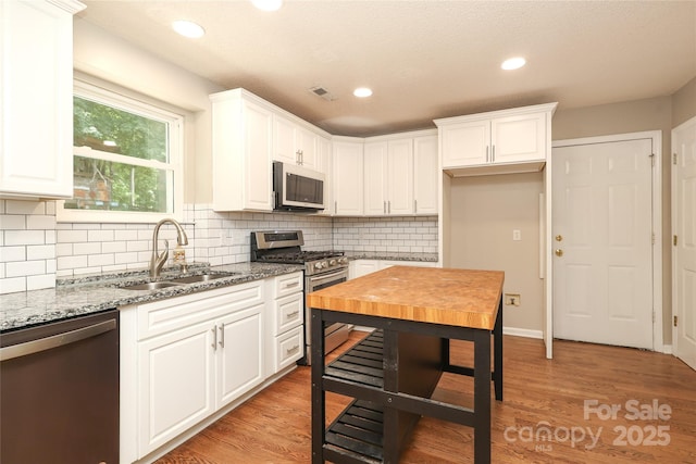 2011 Redwood Dr, Indian Trail, NC 28079 - kitchen with stainless steel appliances, light stone counters, white cabinets, decorative backsplash, and recessed lighting