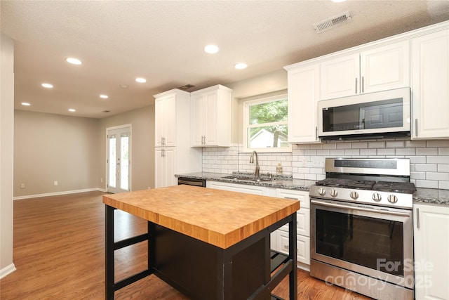 2011 Redwood Dr, Indian Trail, NC 28079 - kitchen featuring gas stove, white microwave, wood counters, tasteful backsplash, and white cabinetry